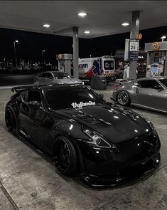 two black sports cars parked at a gas station