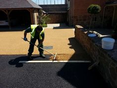 a man in yellow vest using a shovel to clean the pavement on a residential street