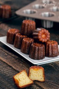 several bundt cakes on a plate with one cut in half and two muffins next to it