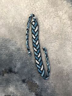 a blue and white braided bracelet laying on the ground