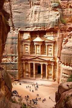 people are standing in front of a building carved into the side of a cliff