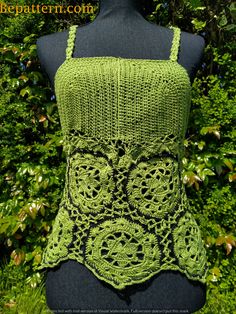 a green crocheted tank top sitting on top of a mannequin head