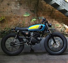 a blue and yellow dirt bike parked in front of a brick wall next to stairs