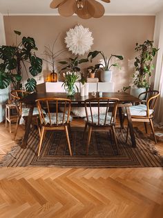 a dining room table and chairs with plants on the wall behind them in front of a fan