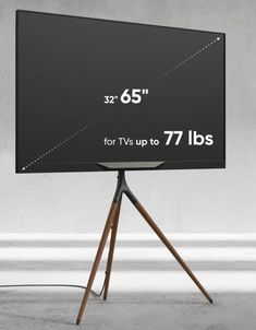 a large screen tv sitting on top of a wooden tripod next to a white wall