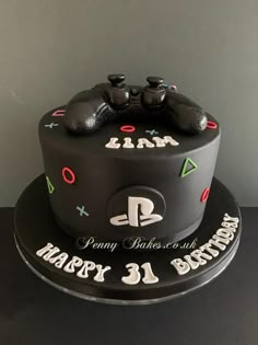 a black birthday cake with two video game controllers on top and happy 31 birthday written on the side