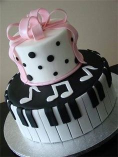 two tiered cake decorated with music notes and pink ribbon on top of each layer