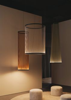 three lamps hanging from the ceiling in a room with two stools and one table