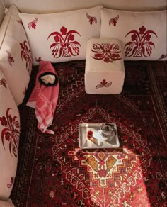 a red and white couch sitting on top of a rug next to a tray filled with food