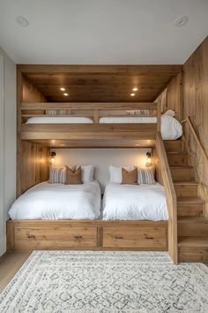 two beds in a wooden bunk bed with white sheets and pillows on top of them