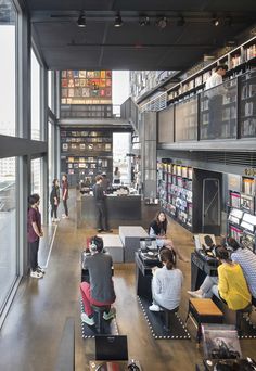 people sitting at tables in a library with lots of bookshelves and shelves full of books