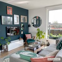 a living room filled with furniture and pictures on the wall above it's windows