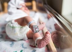 a baby is laying down on the floor with its arm wrapped around an adult's wrist