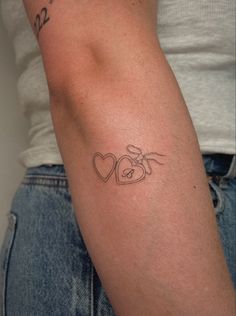 a woman's arm with a tattoo on it that has two hearts in the middle