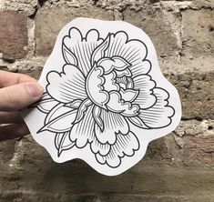 a hand holding up a sticker with an image of a flower in black and white