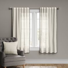 a gray chair sitting in front of a window next to a white rug on top of a hard wood floor