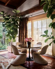 a dining room table with four chairs and a potted plant in the center on top of it