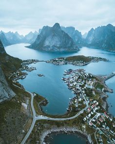 an aerial view of a small town by the water with mountains in the back ground