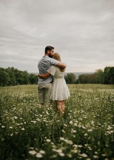 a man and woman embracing in the middle of a field