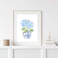 a blue and white vase with flowers in it on top of a shelf next to books