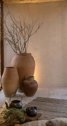 three vases sitting on top of a rug in front of a window with plants growing out of them