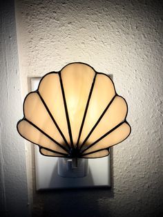 a light that is on the side of a wall with a shell shaped glass shade