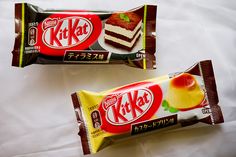 two packets of kitkat's are sitting on a white sheet with an apple in the middle