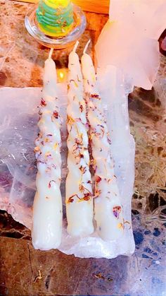 three white candles sitting on top of a table next to a glass bowl and candle holder