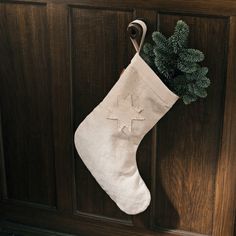 a christmas stocking hanging on a door with a pine tree in the corner next to it