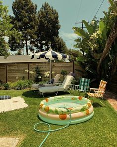 an inflatable pool with lounge chairs and umbrellas around it on the lawn