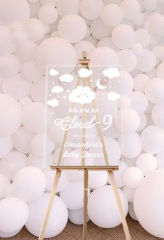 an easel stands in front of white balloons with the words, it's one cloud