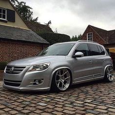 a silver car parked in front of a brick building on a cobblestone road