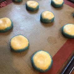 blue and yellow cookies sitting on top of a cookie sheet covered in baking powder, ready to go into the oven