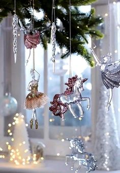 christmas ornaments hanging from a tree in front of a window