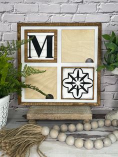 a wooden frame with letters and numbers on it next to a potted plant in front of a brick wall