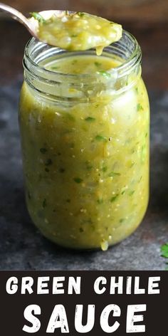 a jar filled with green chile sauce on top of a black counter next to some parsley