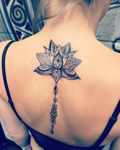 the back of a woman's neck with a lotus tattoo on it