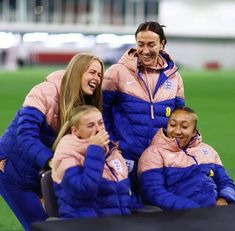 a group of women sitting on top of a soccer field