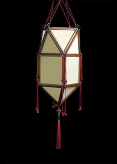 a hanging light fixture with red tassels on it's sides and a white square in the middle