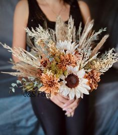 a woman holding a bouquet of dried flowers