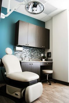 a room with a chair, sink and cabinets in it that has a clock on the wall