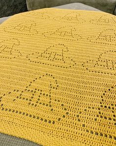 a yellow crocheted blanket sitting on top of a couch next to a pillow