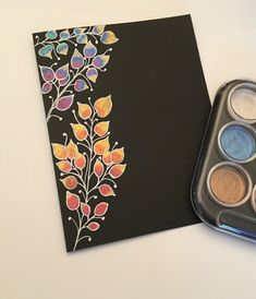 an artistically designed notebook with watercolors in it and a tin of eyeshades