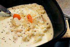 a black bowl filled with soup next to crackers