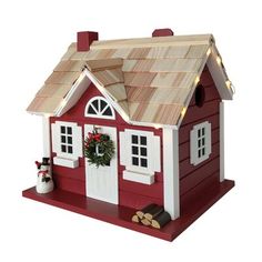 a red and white birdhouse with a wreath on the roof, lights around the windows