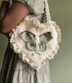 a woman holding a crocheted heart shaped purse with an owl on the front