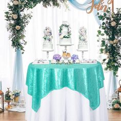 a table topped with two tiered cakes covered in green and white frosting next to flowers