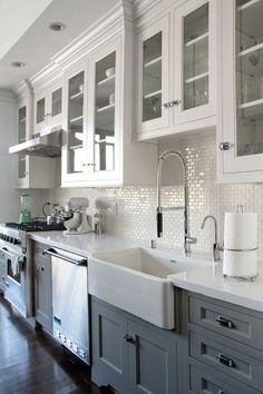 a clean kitchen with white cabinets and stainless steel appliances on the countertop, along with an island style sink