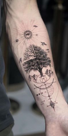 a man's arm with a tree and compass tattoo on the left inner forearm