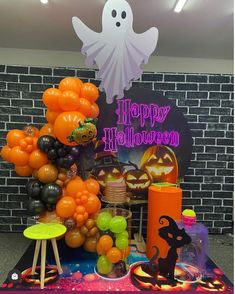 a table topped with lots of balloons and halloween decorations in front of a brick wall